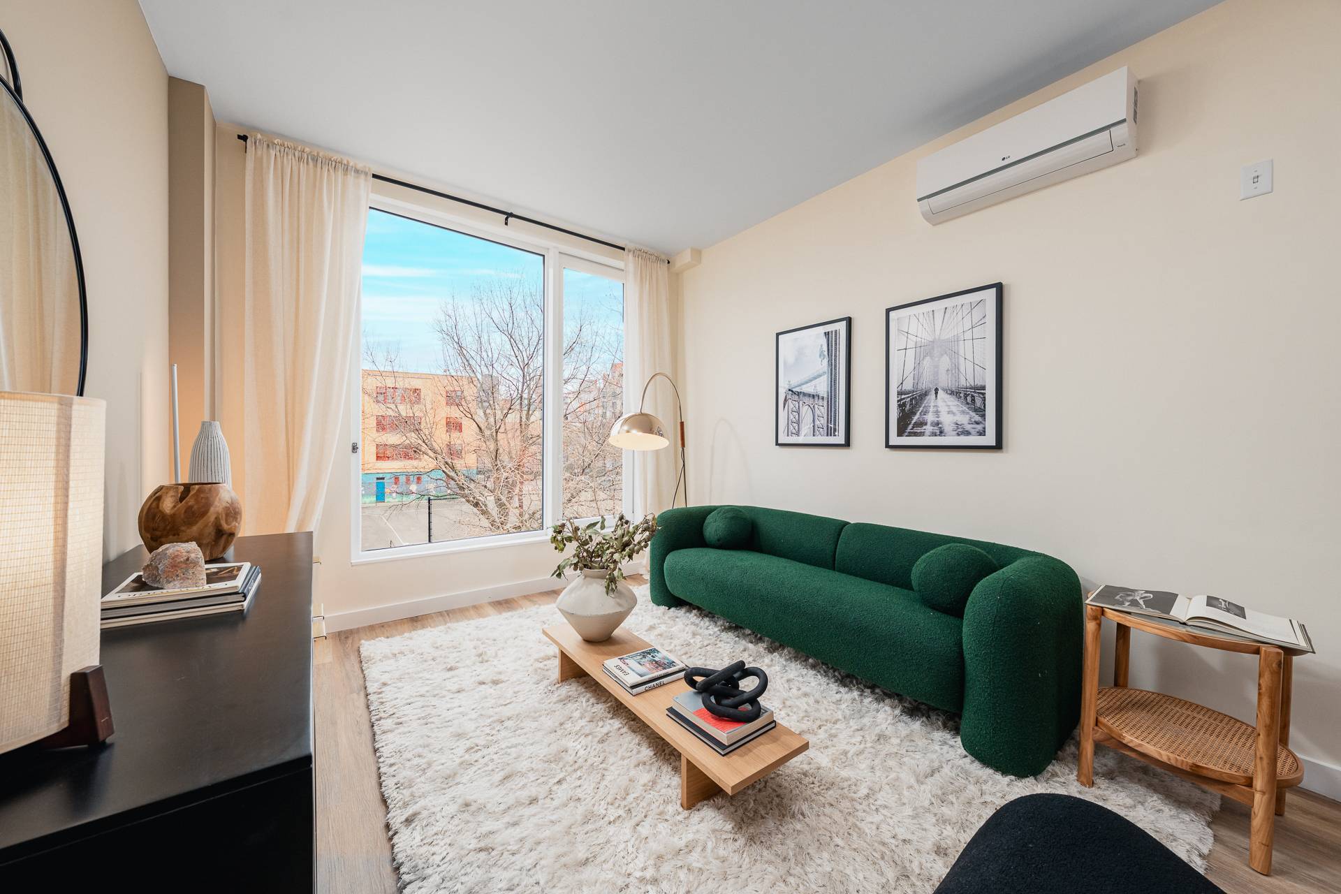 bright, modern, living room with modern couch, tables, photography on walls, with carpet on wood floors and large window