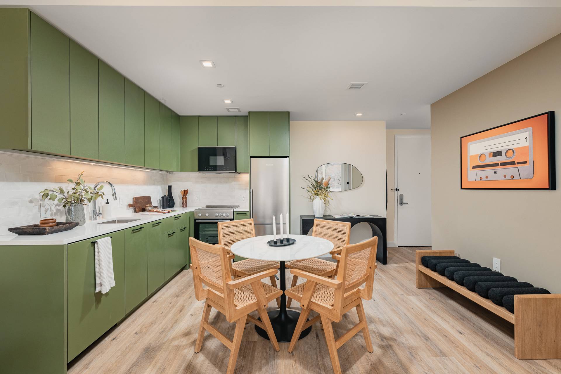 Open Kitchen & Dining with green tone cabinets, light countertops, round table with 4 chairs and wood floors