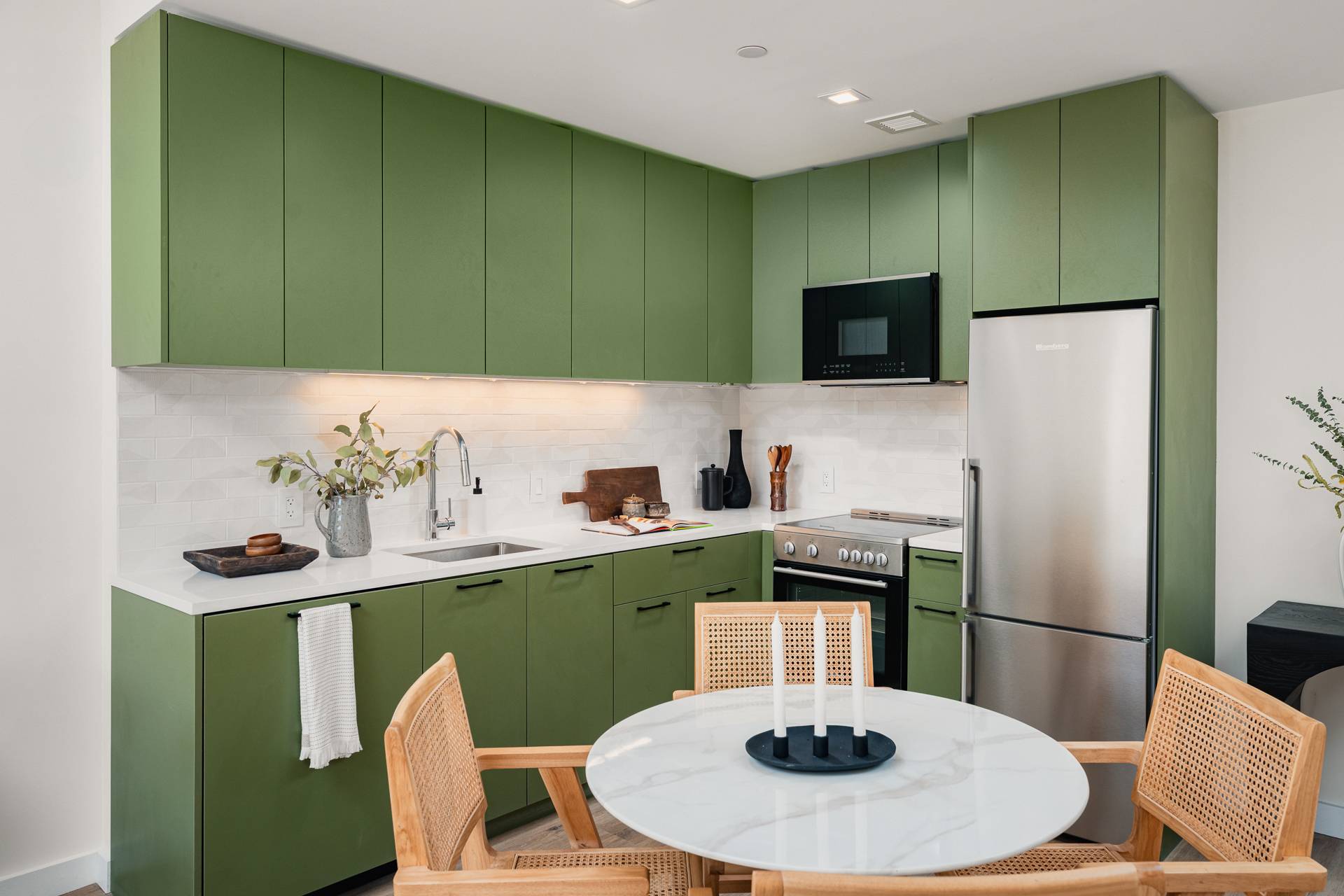 Kitchen & Dining with green tone cabinets, light countertops, round table with 4 chairs, SS fridge and stove/oven