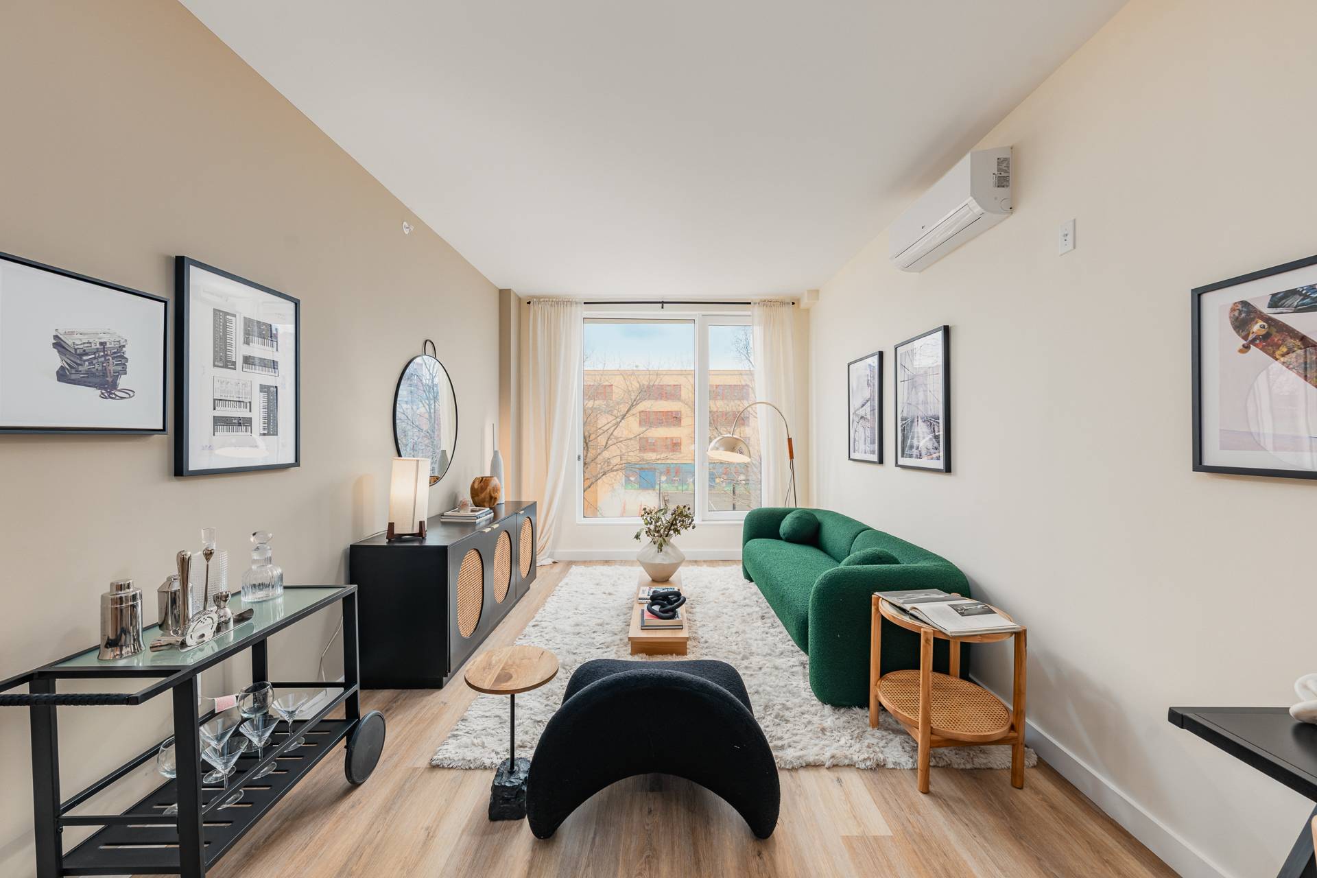bright, modern, living room with modern couch, seating, tables, bar card, artwork, with wood floors and large window