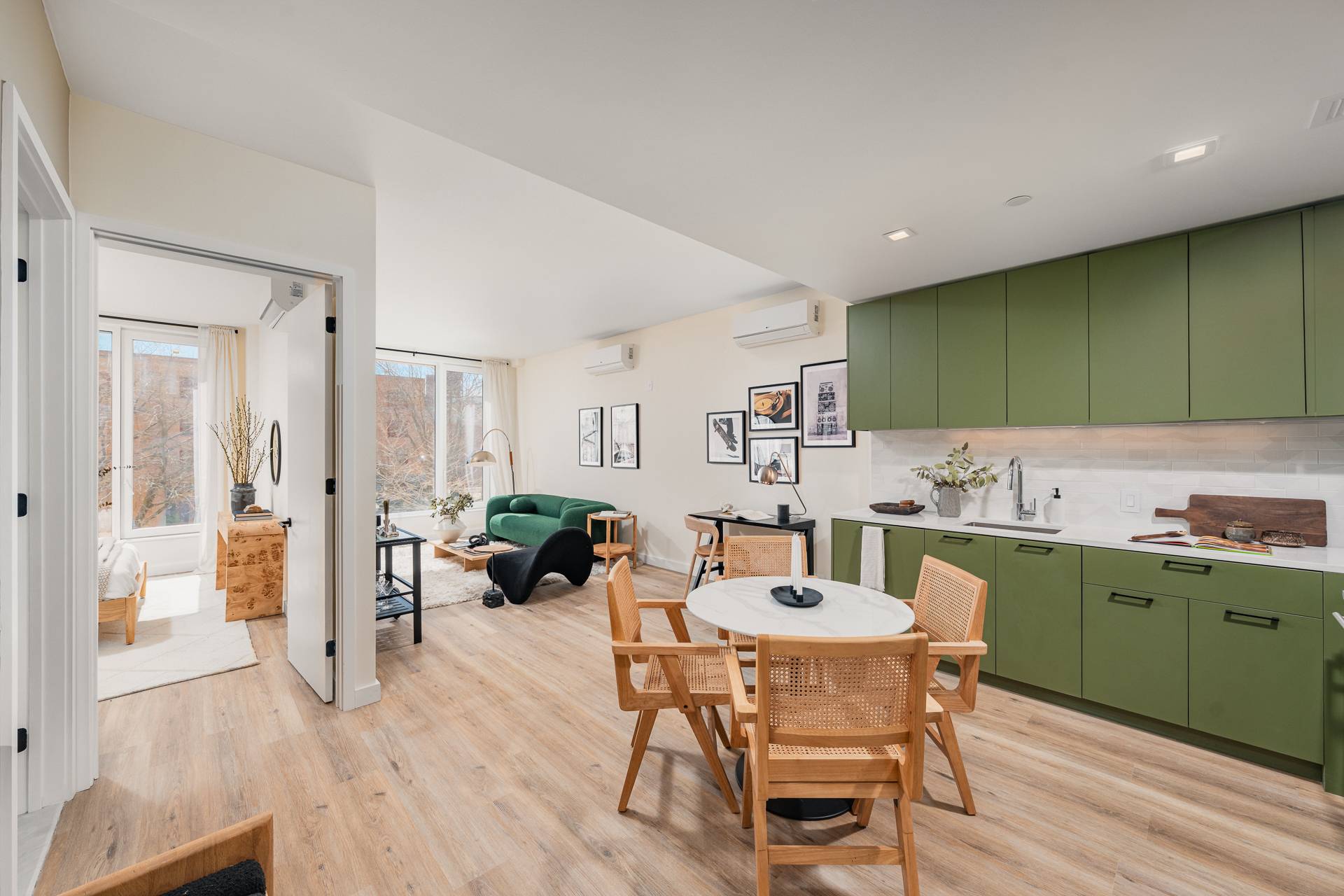 Open Kitchen and Dining with food floors, living room with couch, table and seating with large windows and open bedroom door to the side
